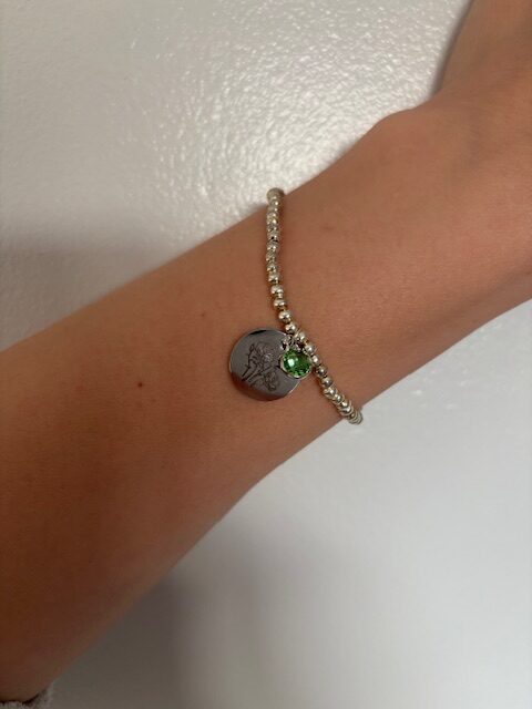 Silver plated beaded bracelet with green August birth stone and silver engraved image of a poppy on a charm.