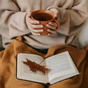 Women holding mug of coffee reading a book
