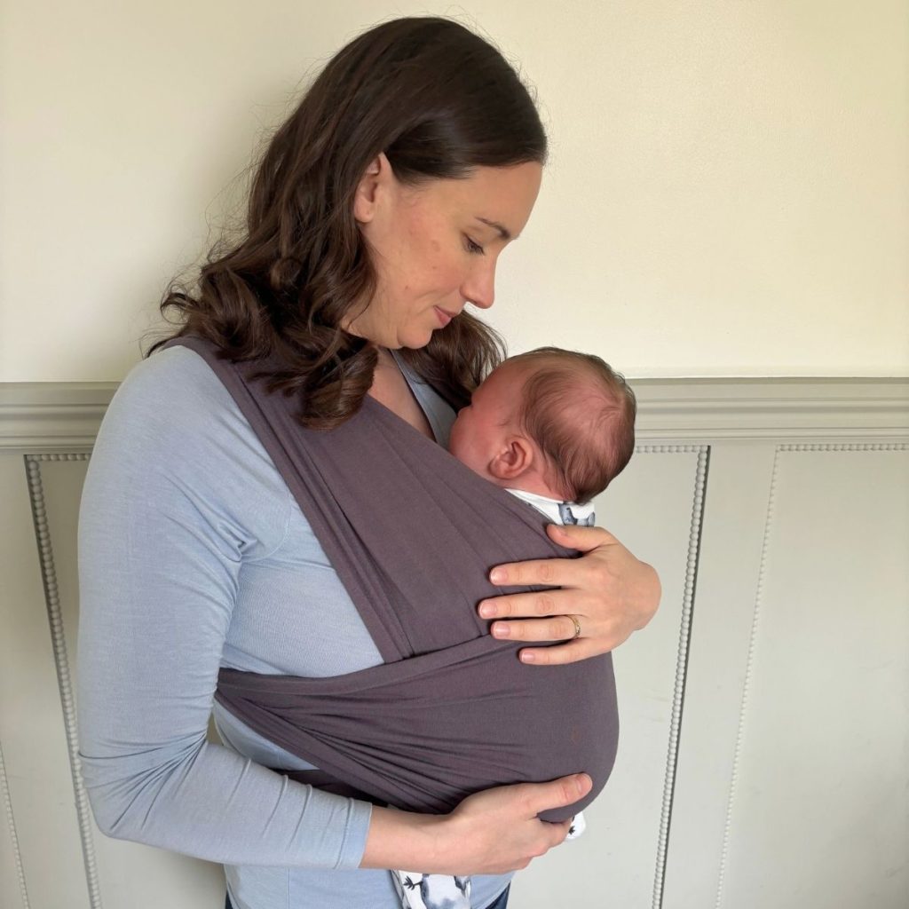Author of Green Homemaking wearing her newborn baby in a grey fabric wrap.