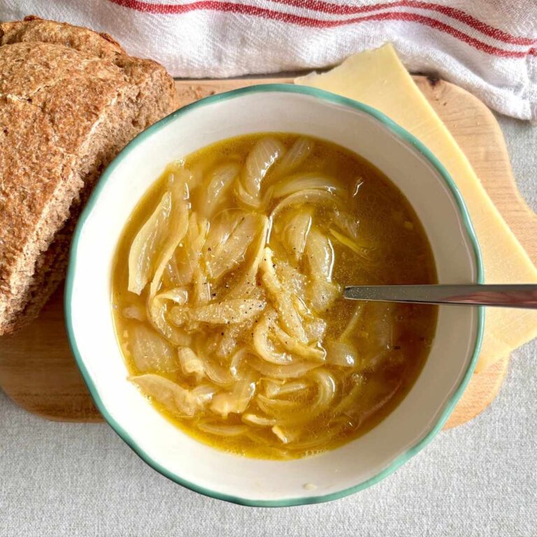 French Onion Soup with brown bread and cheese on butting board