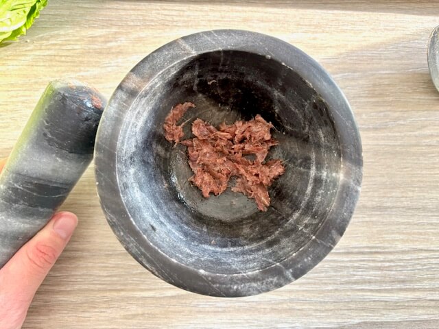 Crushed anchovy fillets in pestle and mortar