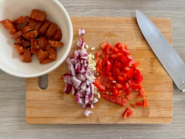 Chopped chorizo, red onion, garlic and red pepper on chopping board