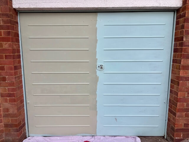 Garage door half painted in the colour 'Wise Old Sage' and the other half showing old paint colour, which is light blue.