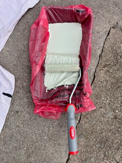 Roller coated in paint inside of a tray lined with a plastic bag