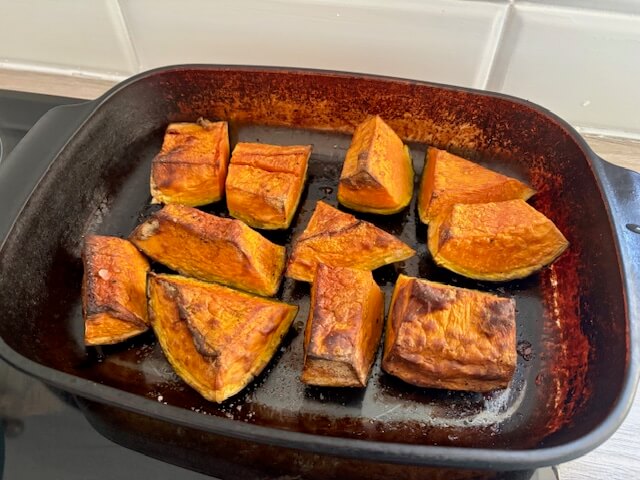 Slices of pumpkin on a baking tray that have been roasted in the oven