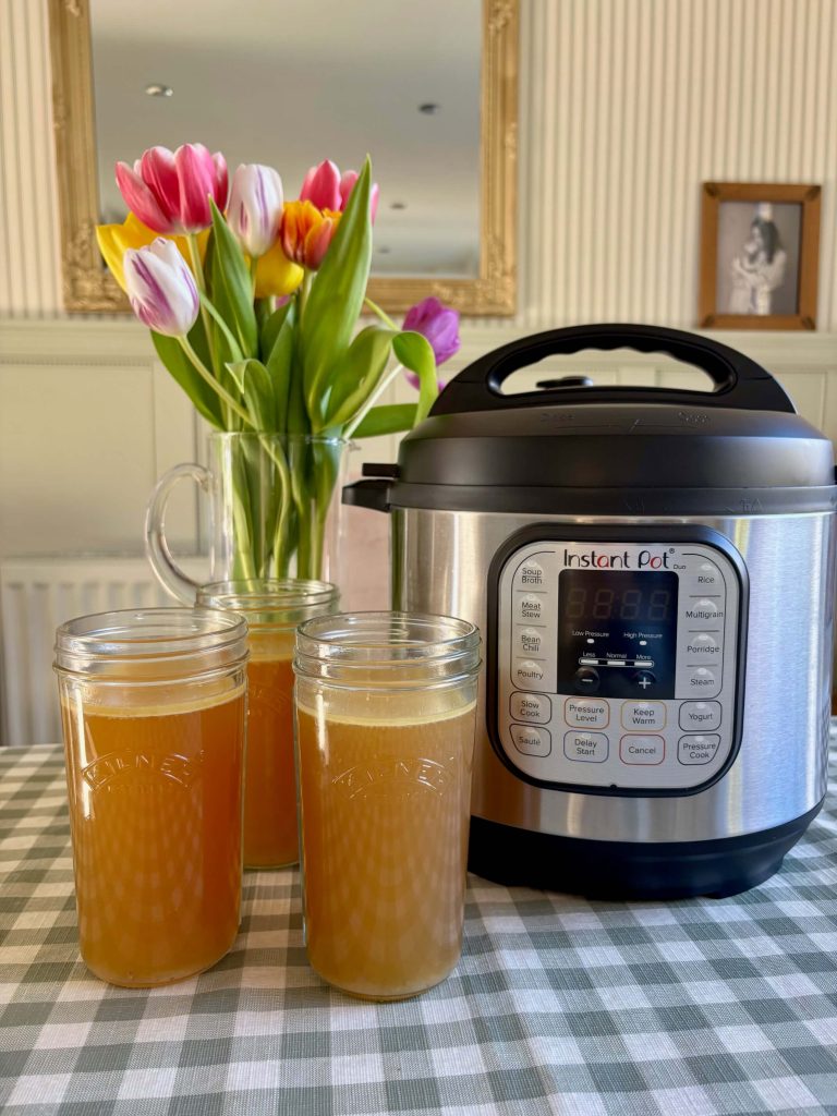 Instant Pot next to 3 glass jars containing Bone Broth