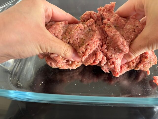 Hands mixing lamb and spices together